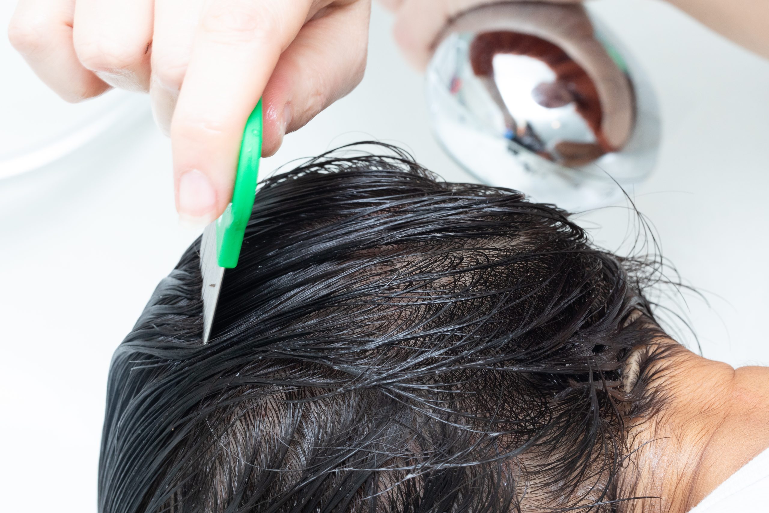 Fine-tooth lice comb moving through wet hair during treatment.