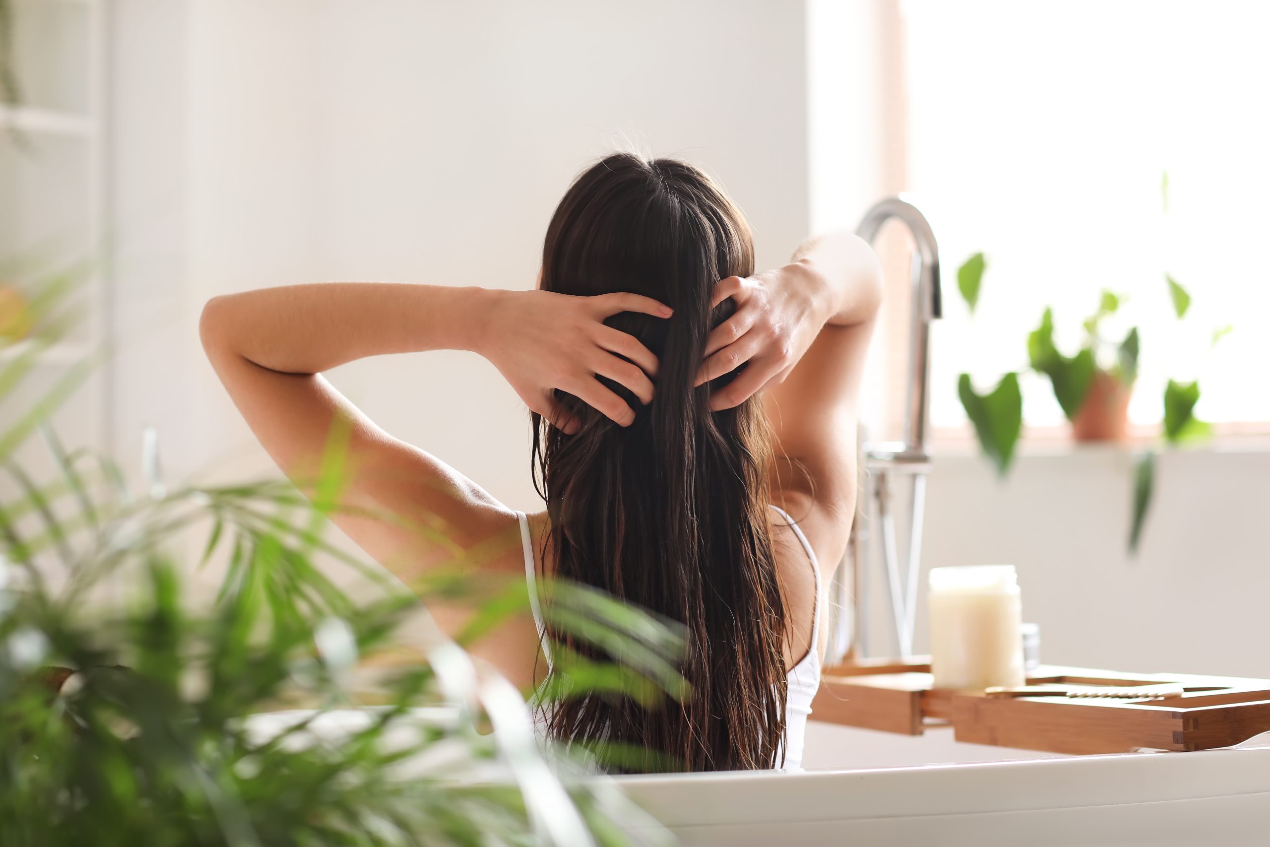 Woman applying coconut oil to her hair beside a fine-tooth lice comb.