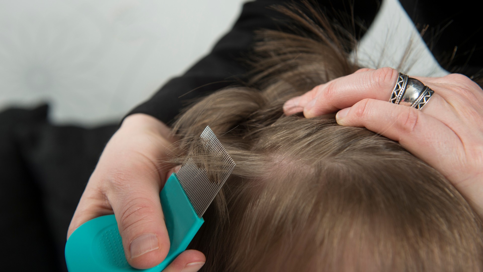 Close-up of a parent checking a child's hair during a lice treatment discussion.