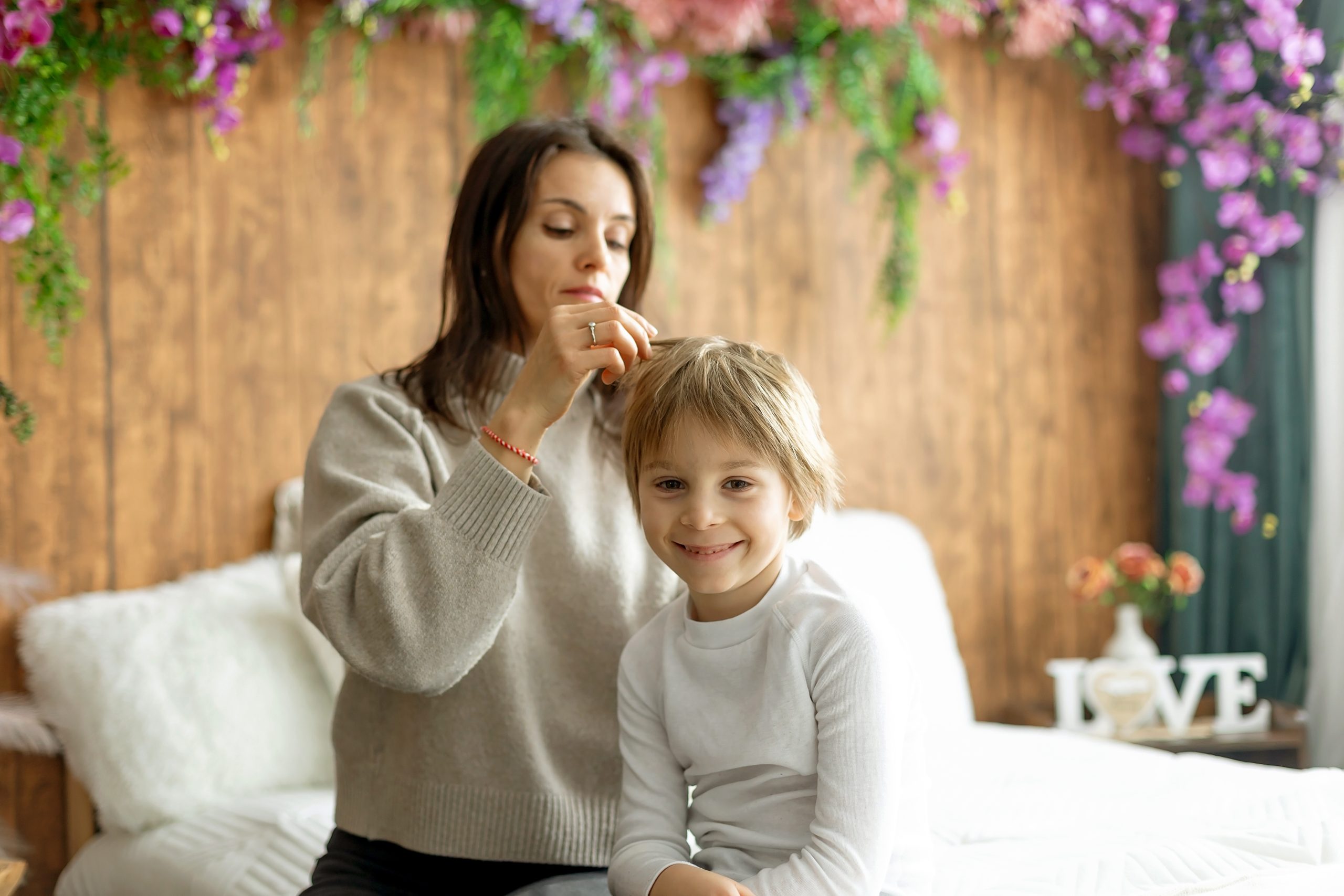 Mother checking her son's hair for head lice with a fine-tooth comb.