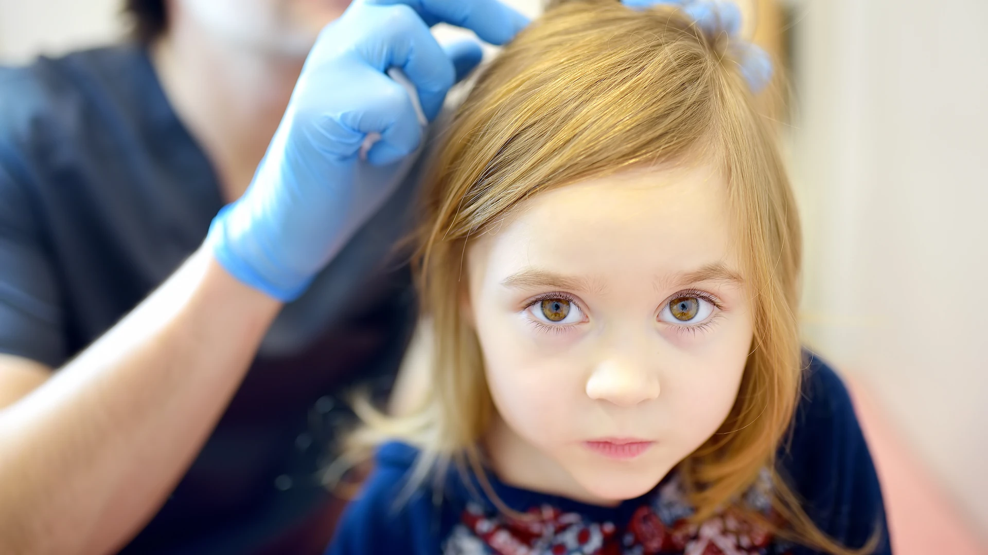 Professional checking a child's hair and scalp for head lice at a clinic