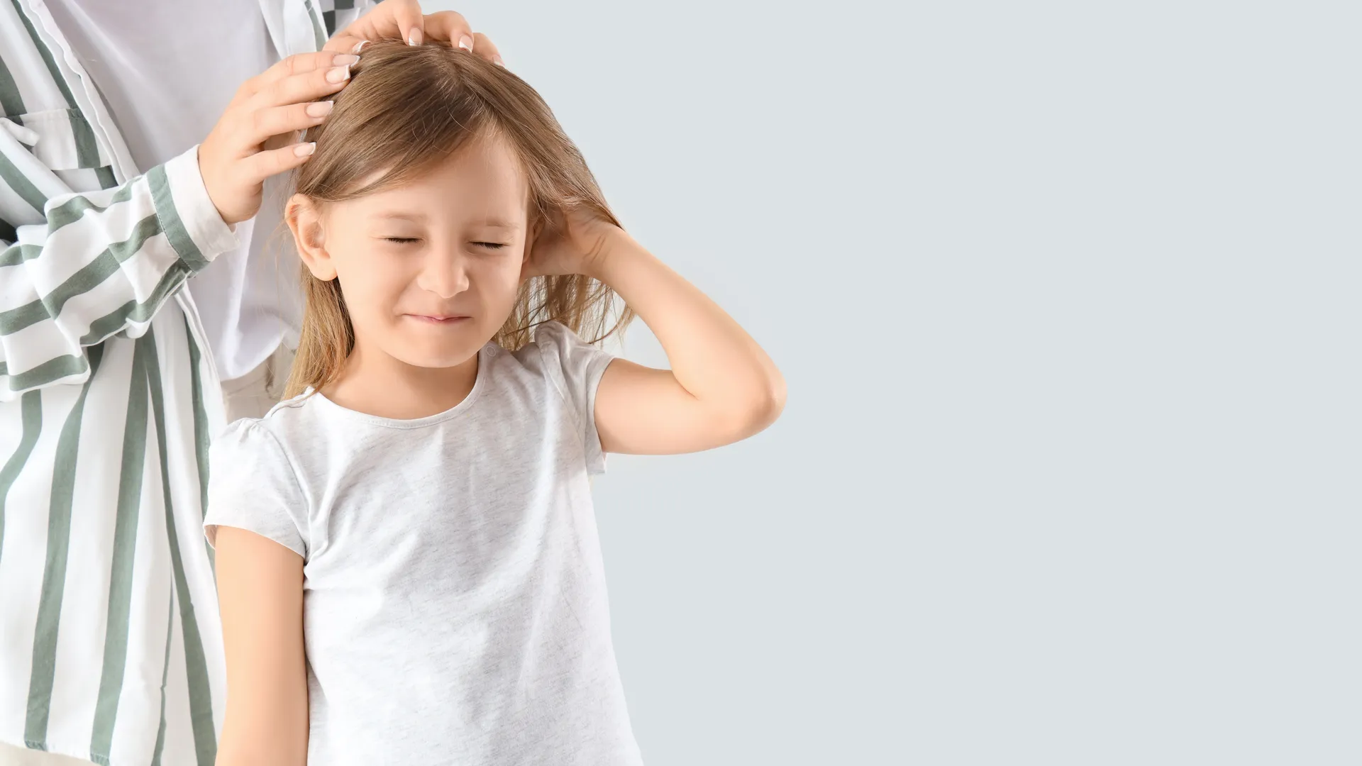 Mother checking her daughter's scalp for head lice before summer camp