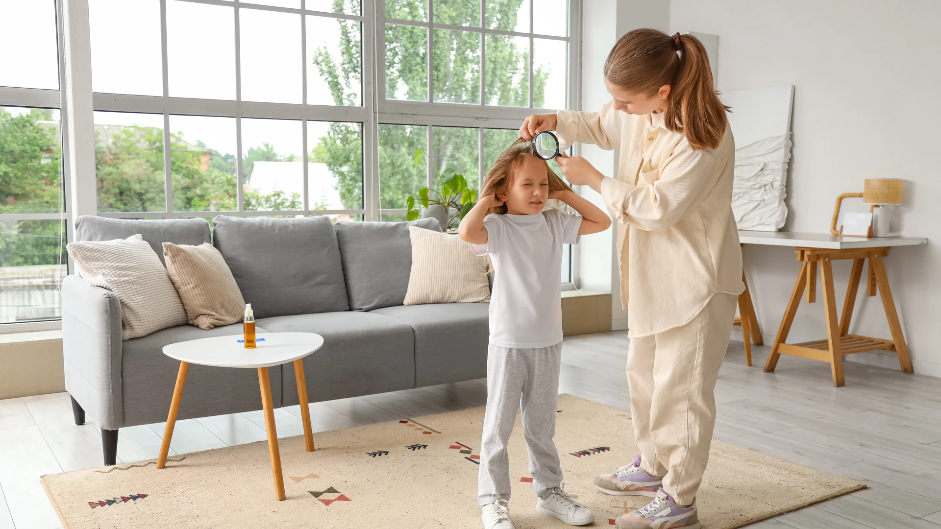 Parent checking a child's hair with a magnifying glass for head lice