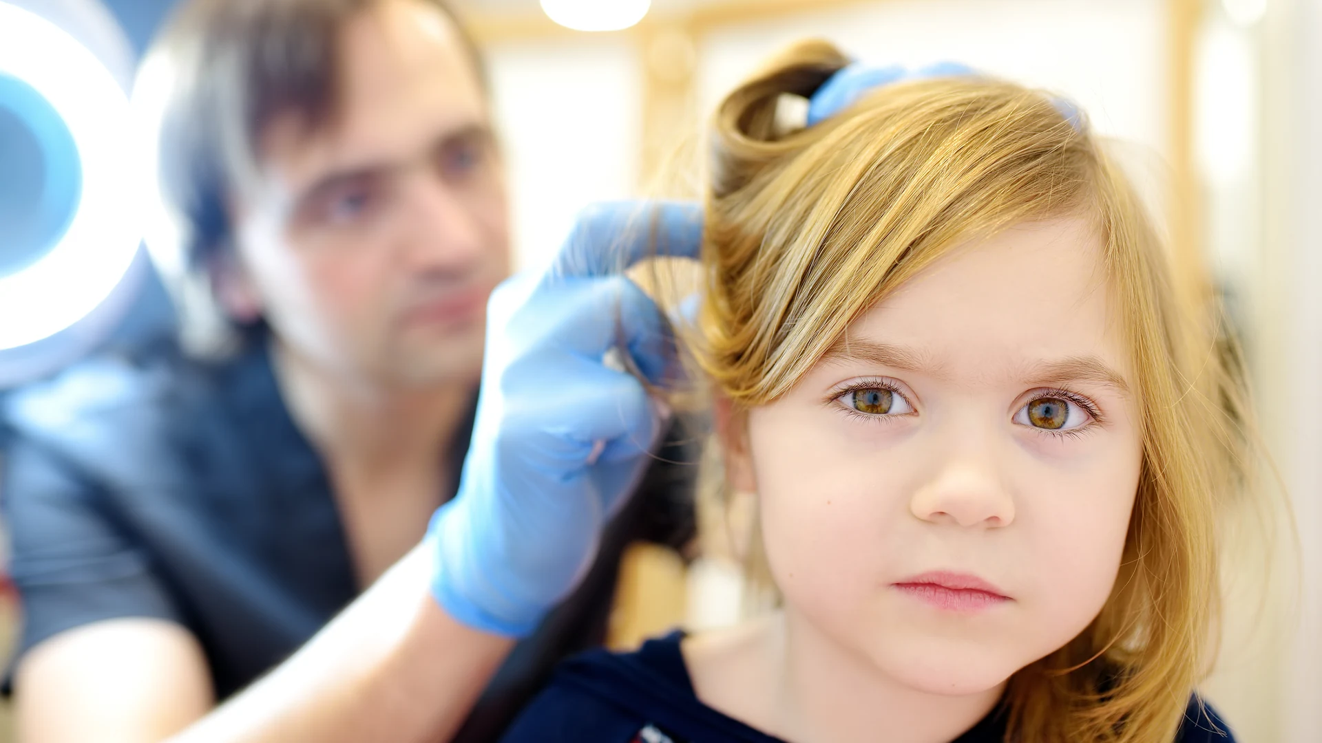 Professional examining a child's hair and scalp for head lice and nits