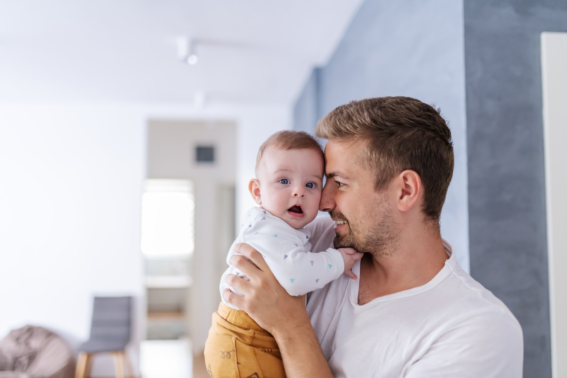 Bearded father holding a young child with their heads pressed together