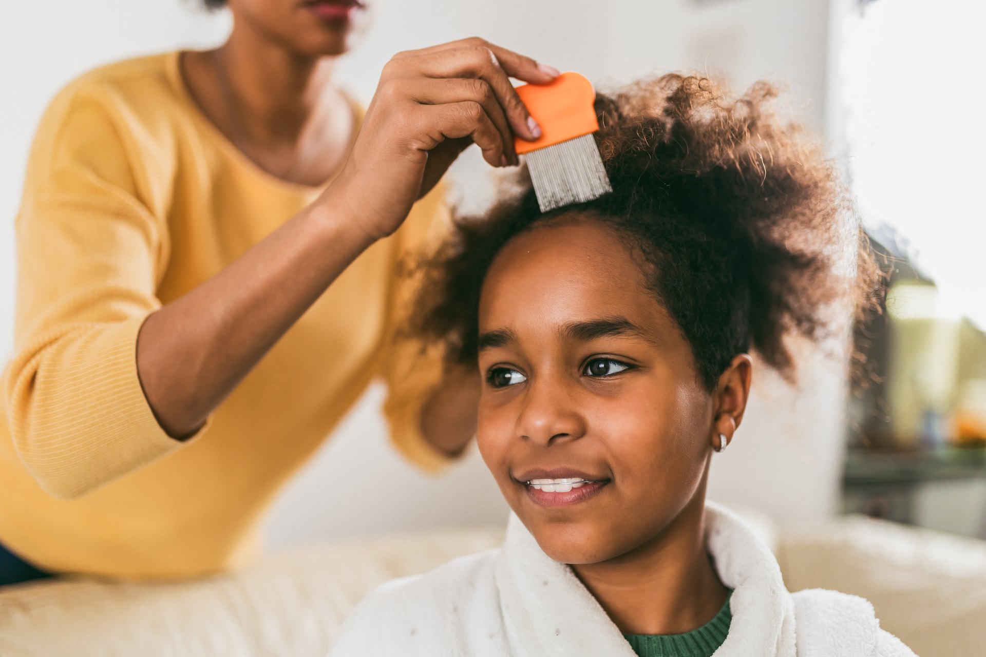 Parent using a metal fine-tooth nit comb on a child's hair at home