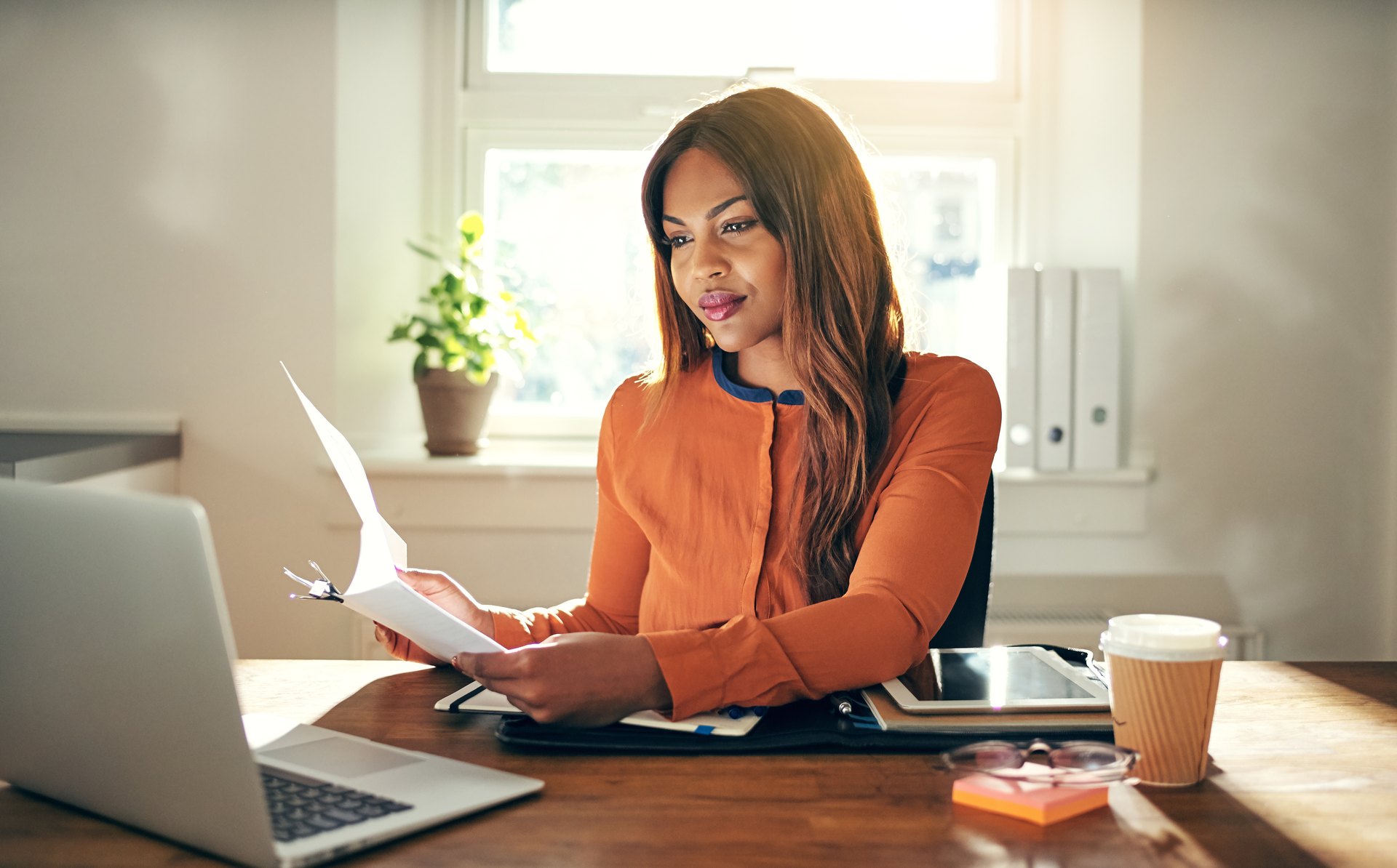 Business owner at a home office desk reading a multi-page printed document
